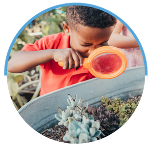 Black boy with magnifying glass looking at garden plants