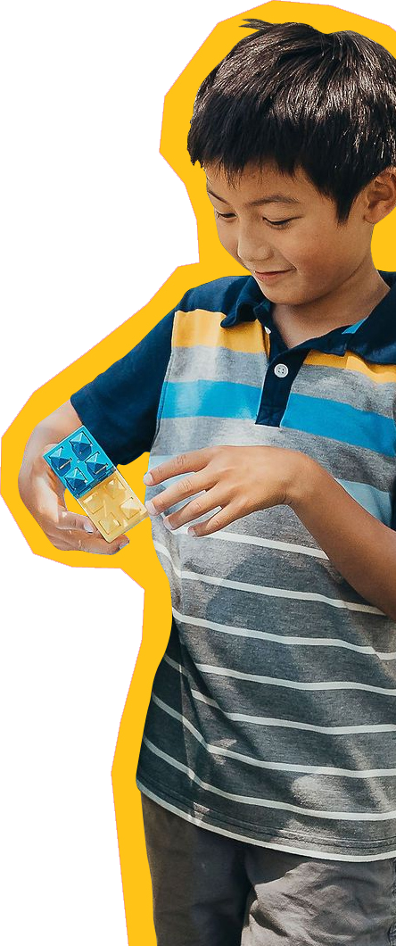 Child at SDCDM smiling while playing with blocks