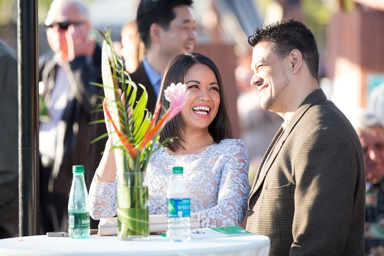 a man and woman looking on and smiling sitting at a table