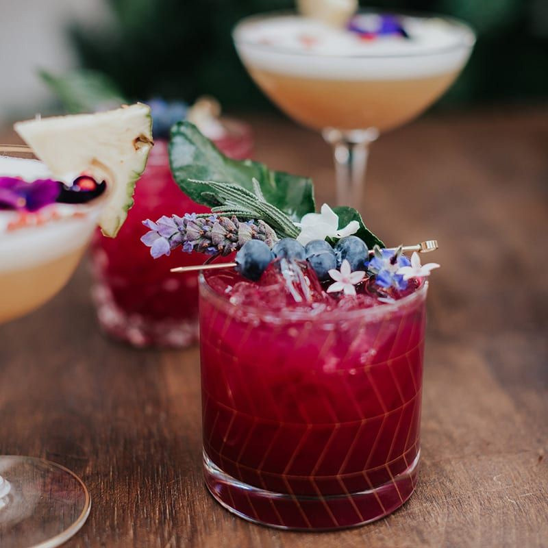 red drink in glass with blueberry garnish