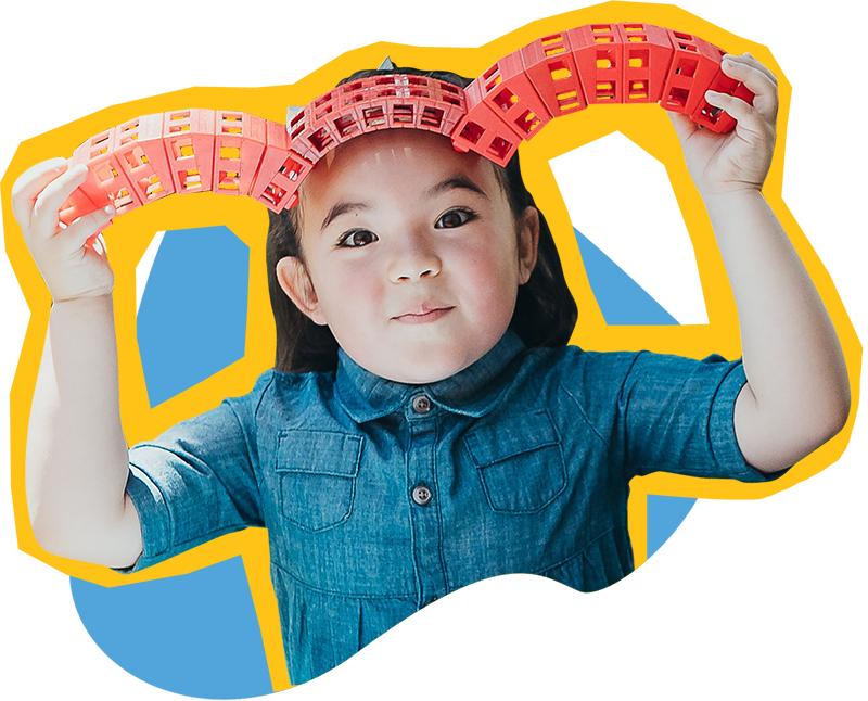 Child at SDCDM playing with blocks while smiling at camera