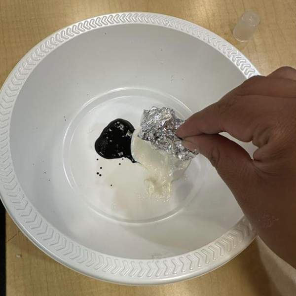 White and black paint in a bowl with crumpled foil.