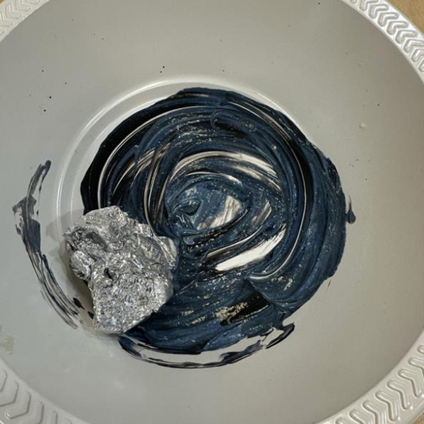 Mixed black and white paint in a bowl.