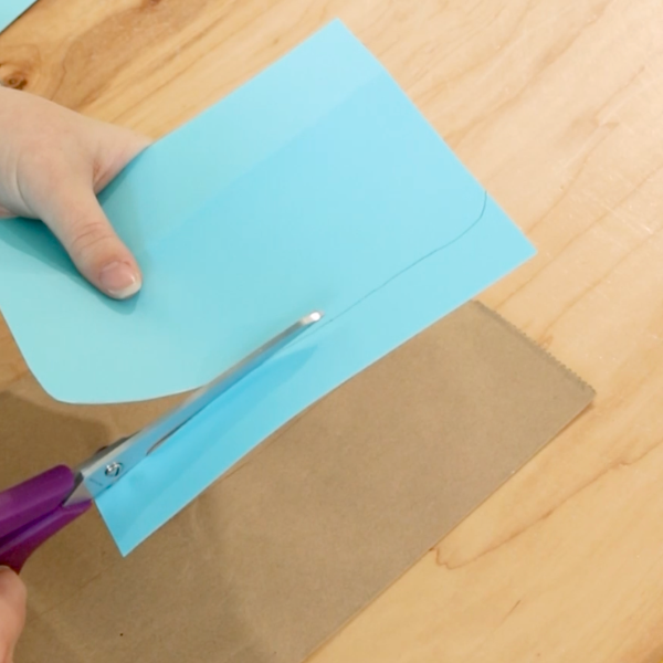 Educator cutting blue paper into pocket.