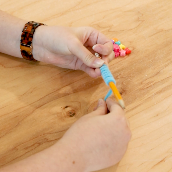 Wrapping pipe cleaner around a pencil.