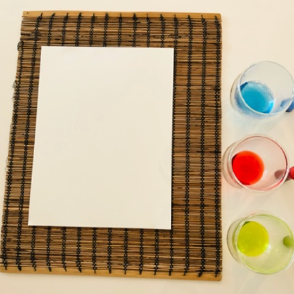 A plain piece of paper with three cups of different colored food dye.