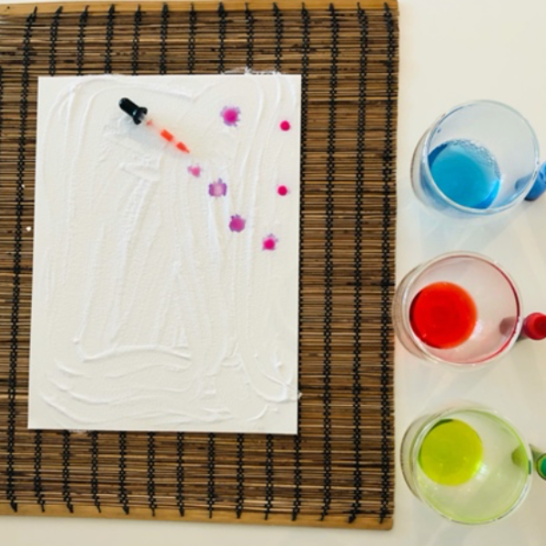 A dropper of vinegar and food dye added to the baking soda layer.