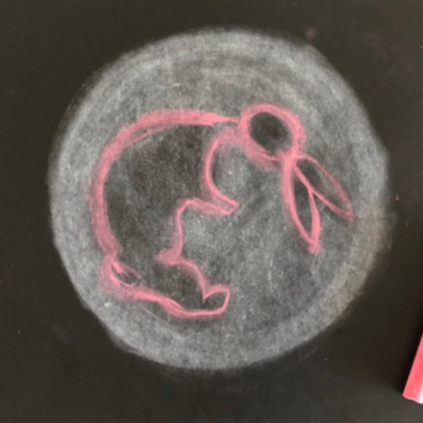 A moon chalk drawing with a pink rabbit design on top.