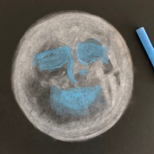 A moon chalk drawing with a smile drawn over top.