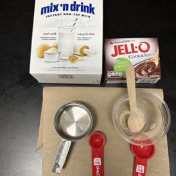 Materials used for the astronaut pudding (powder milk, powder pudding, measuring cups, measuring spoons, and spoon).