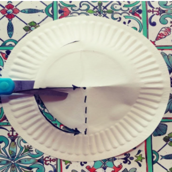 A paper plate being cut on the folded middle line.