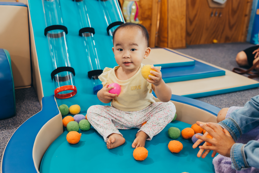 Baby playing in ball pit.